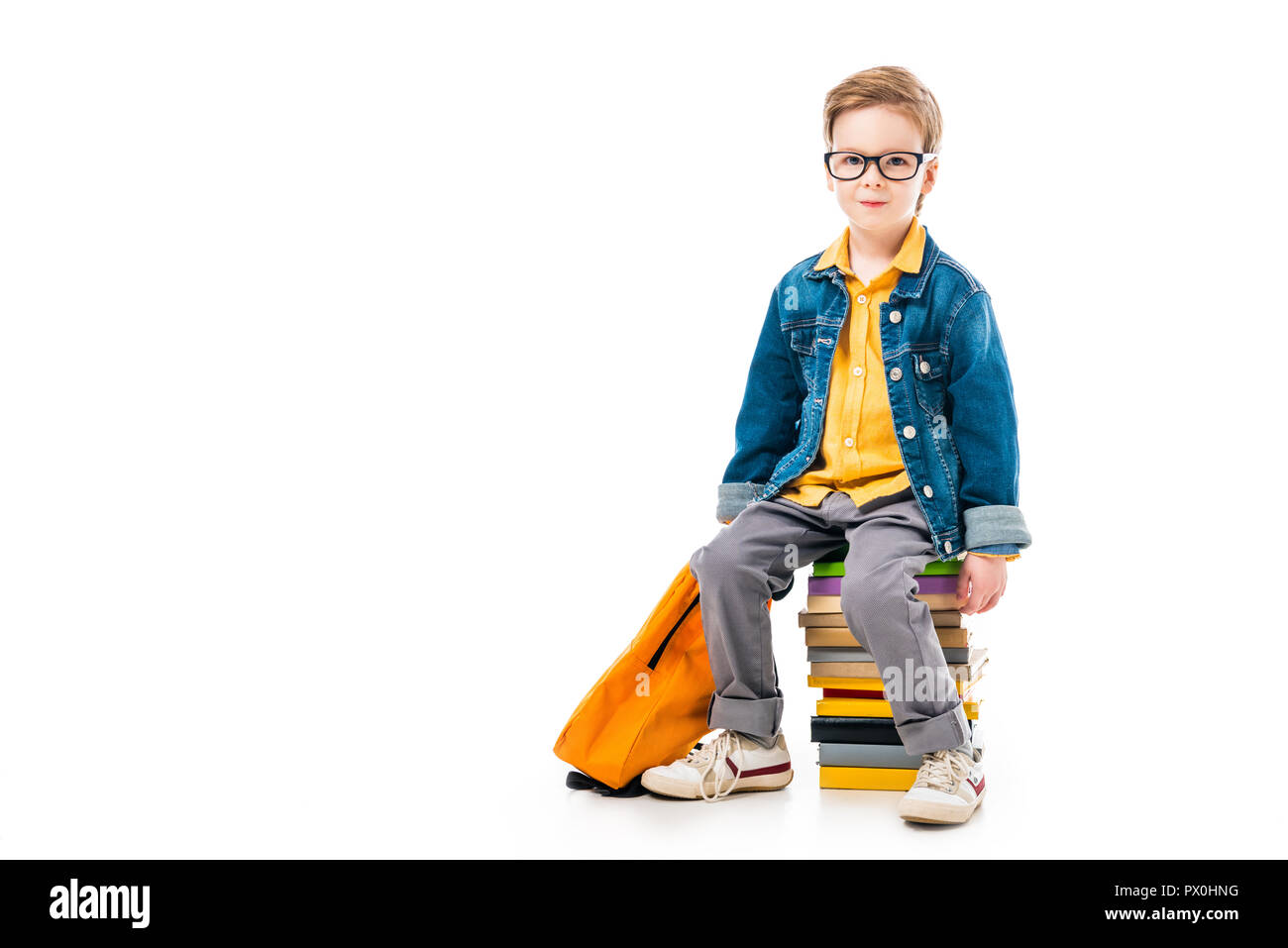 schoolboy sitting on pile of books with backpack, isolated on white Stock Photo