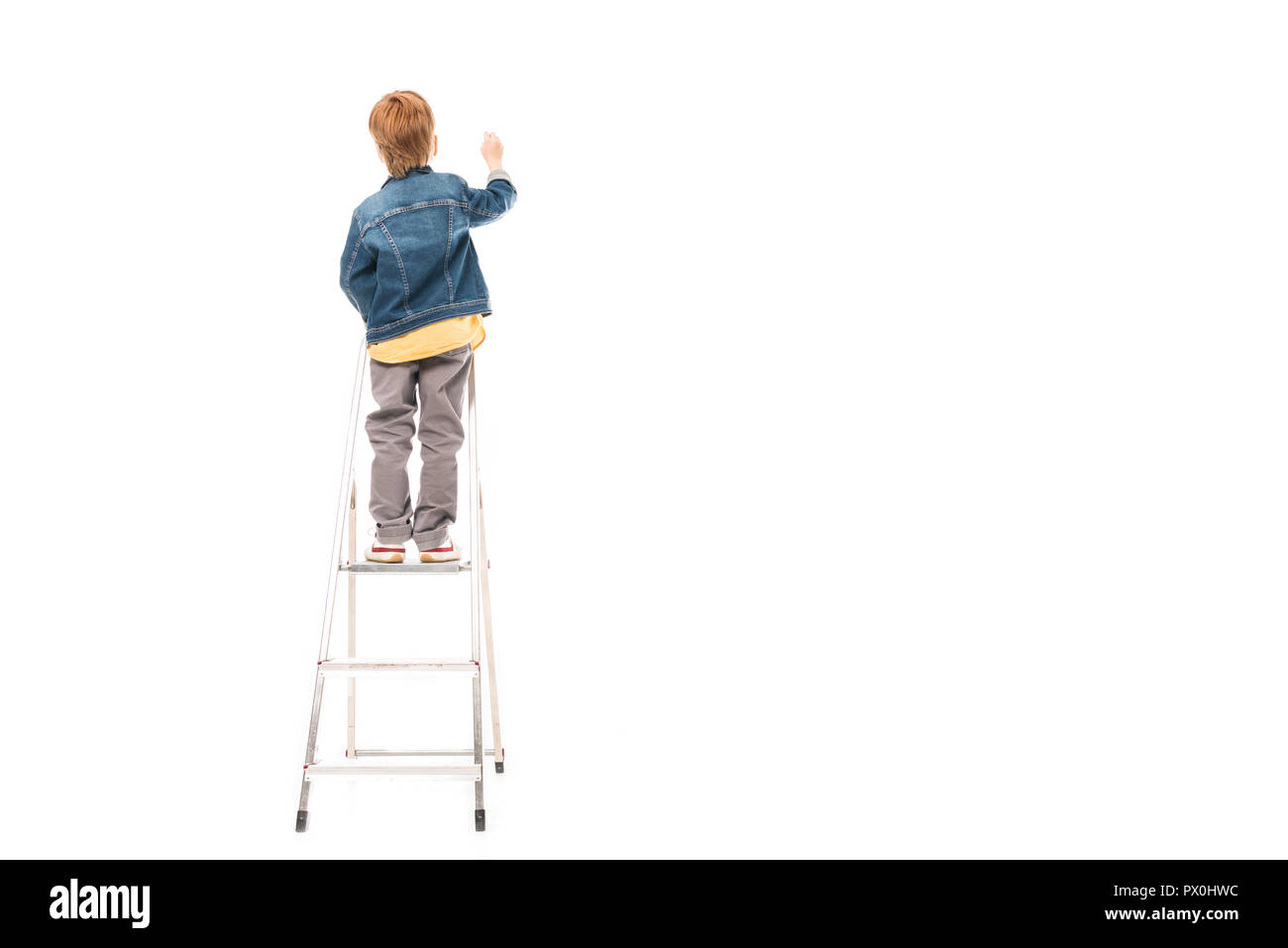 back view of schoolboy standing on ladder and writing isolated on white Stock Photo