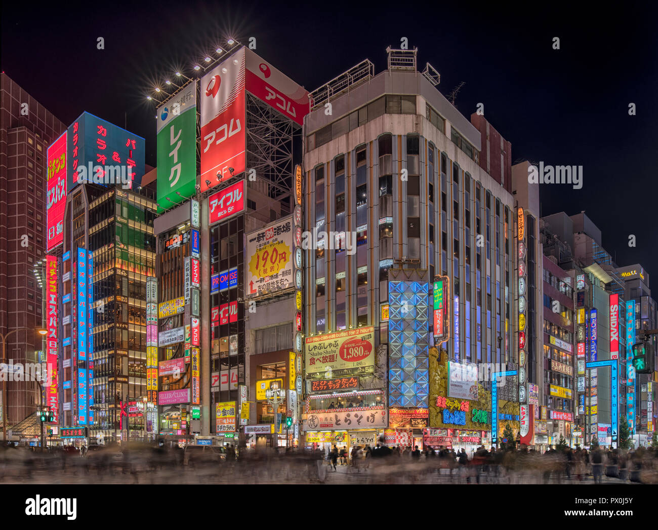 An evening shot in the heart of busy Shinjuku, Toyko, Japan at a busy crossing, with neon signs, the shopping district, neon billboard. Stock Photo