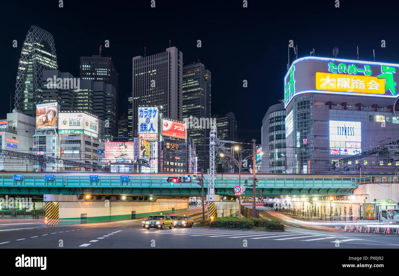 An evening shot in the heart of busy  Shinjuku, Toyko, Japan, with neon signs, office and shopping buildings, billboards, railways and roads. Stock Photo