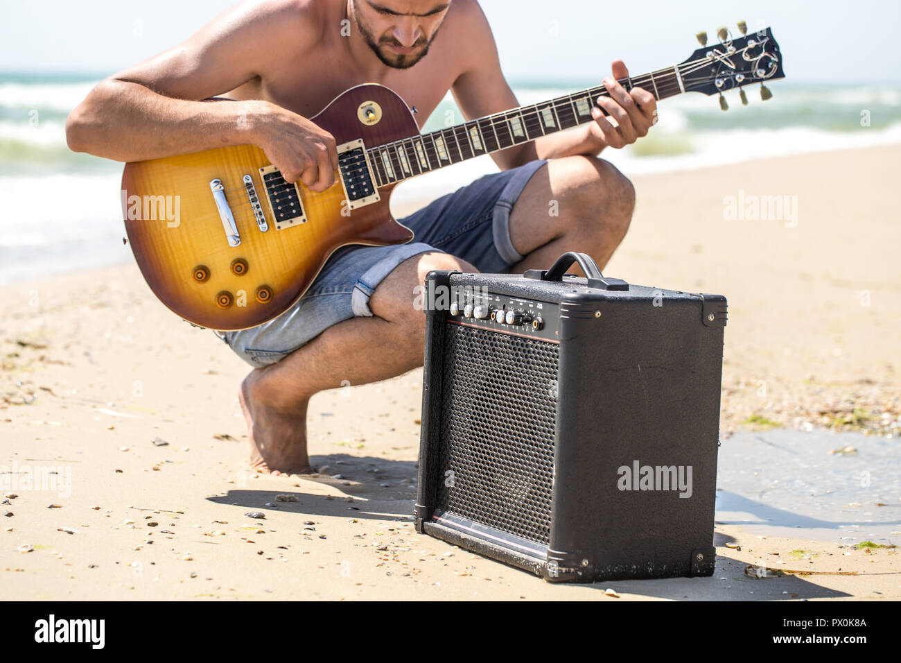 Beachy Instruments young stylish guy on the beach with musical instruments,the concept of ...