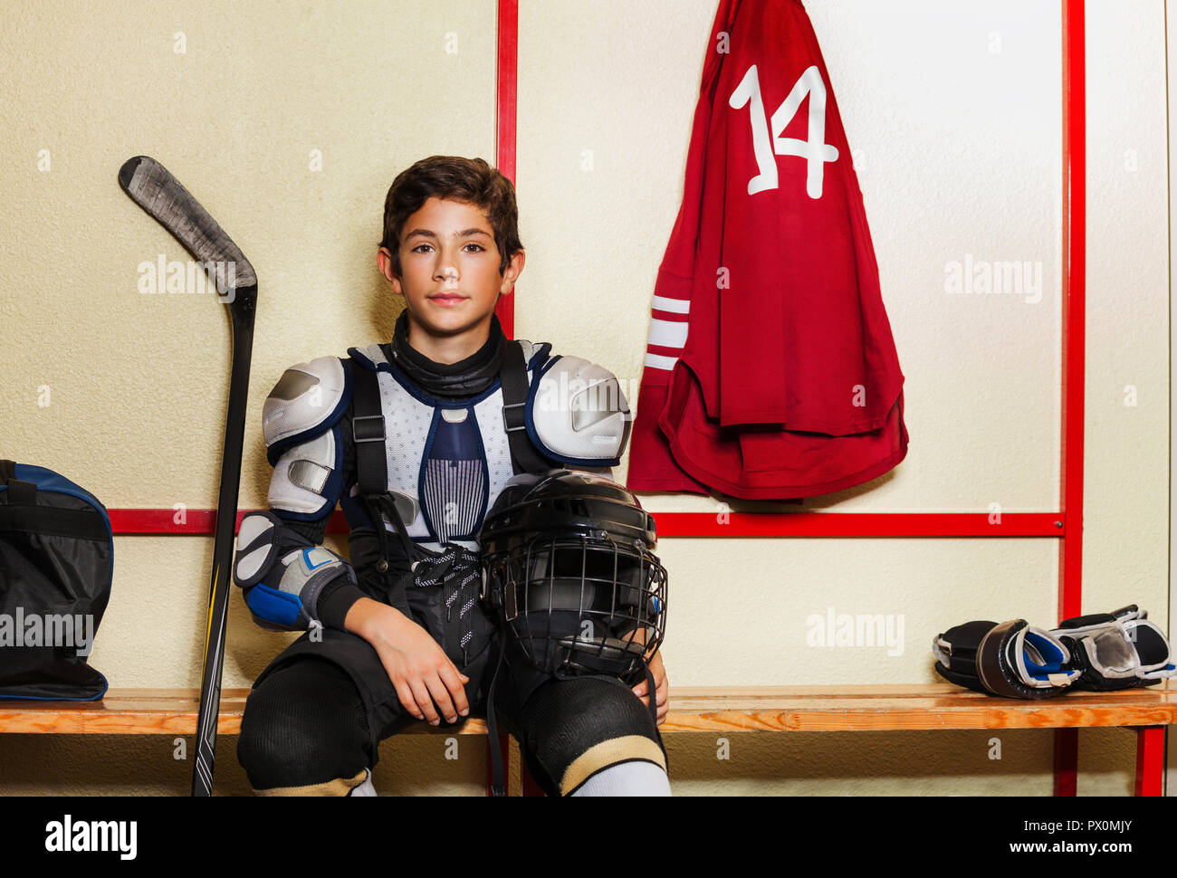 Boy sitting on the bench in ice hockey locker room Stock Photo Alamy
