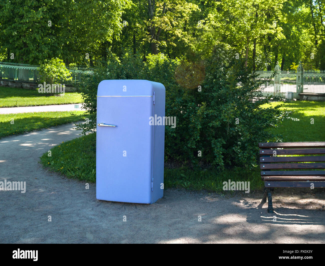 On the street in the park there is an old retro refrigerator of violet color in the summer in sunny weather. Stock Photo