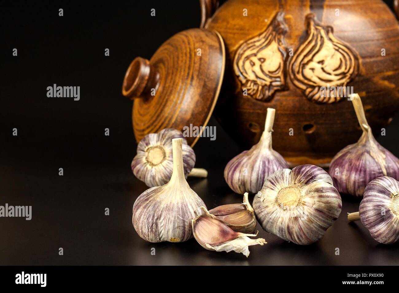 Open garlic on black background table. Whole and split fresh garlic on a black background. Traditional flu and cold treatment. Aromatic spices Stock Photo