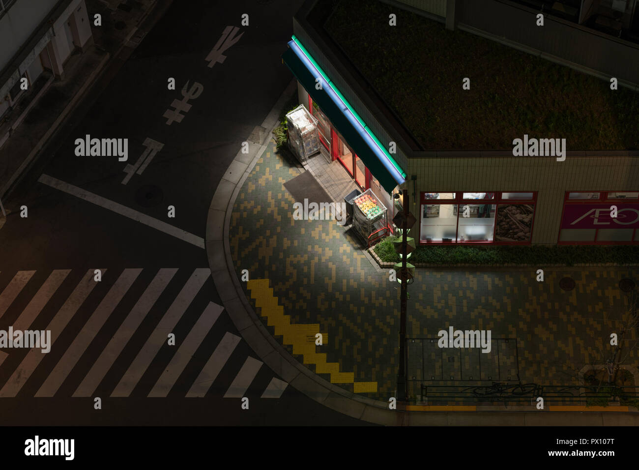 A night, high-angle shot of a street corner shop, in a quiet 