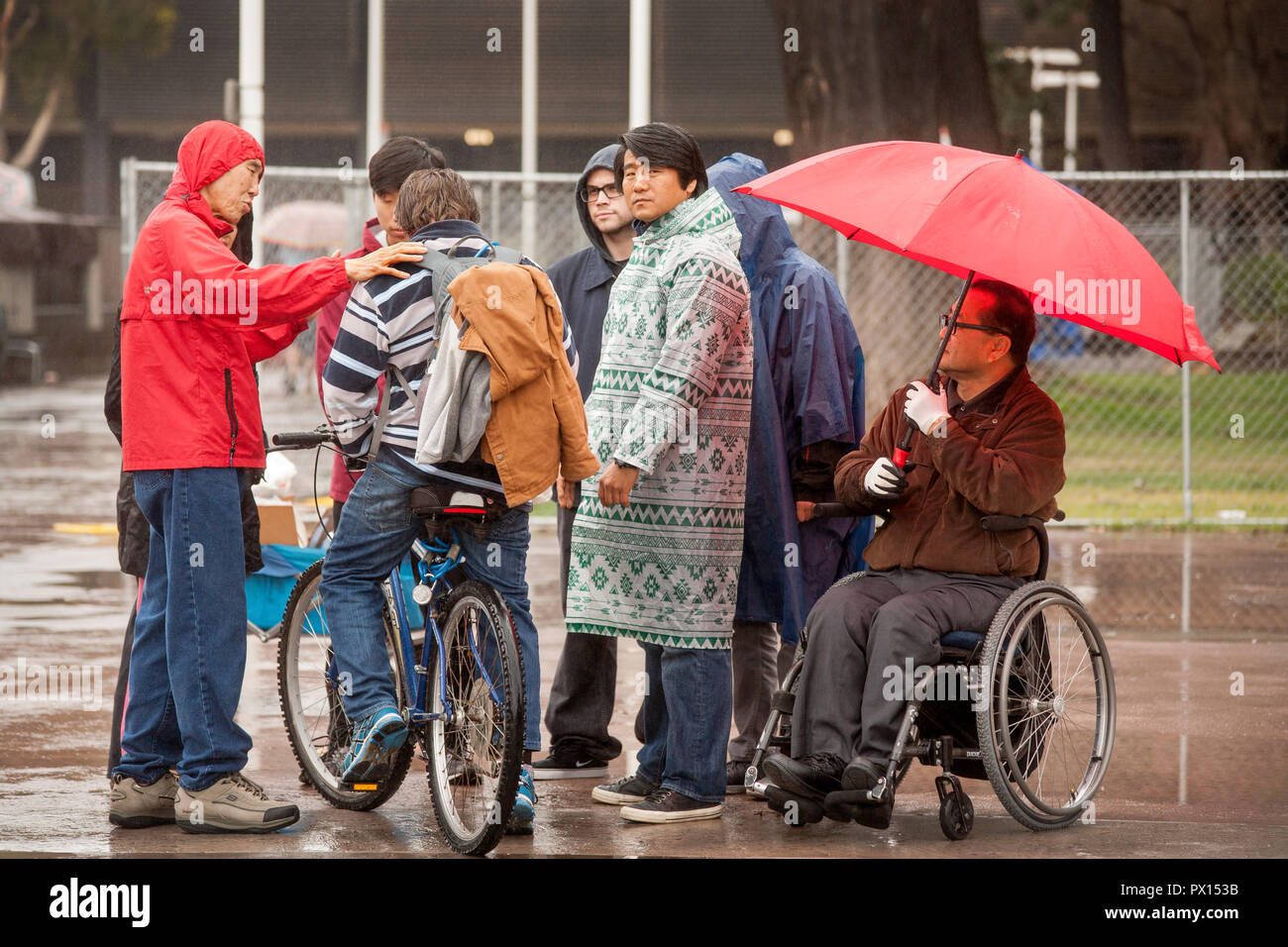 On a rainy afternoon, two evangelical Asian preachers reach out to homeless men at an encampment in Santa Ana, CA.    (Photo by Spencer Grant) Stock Photo