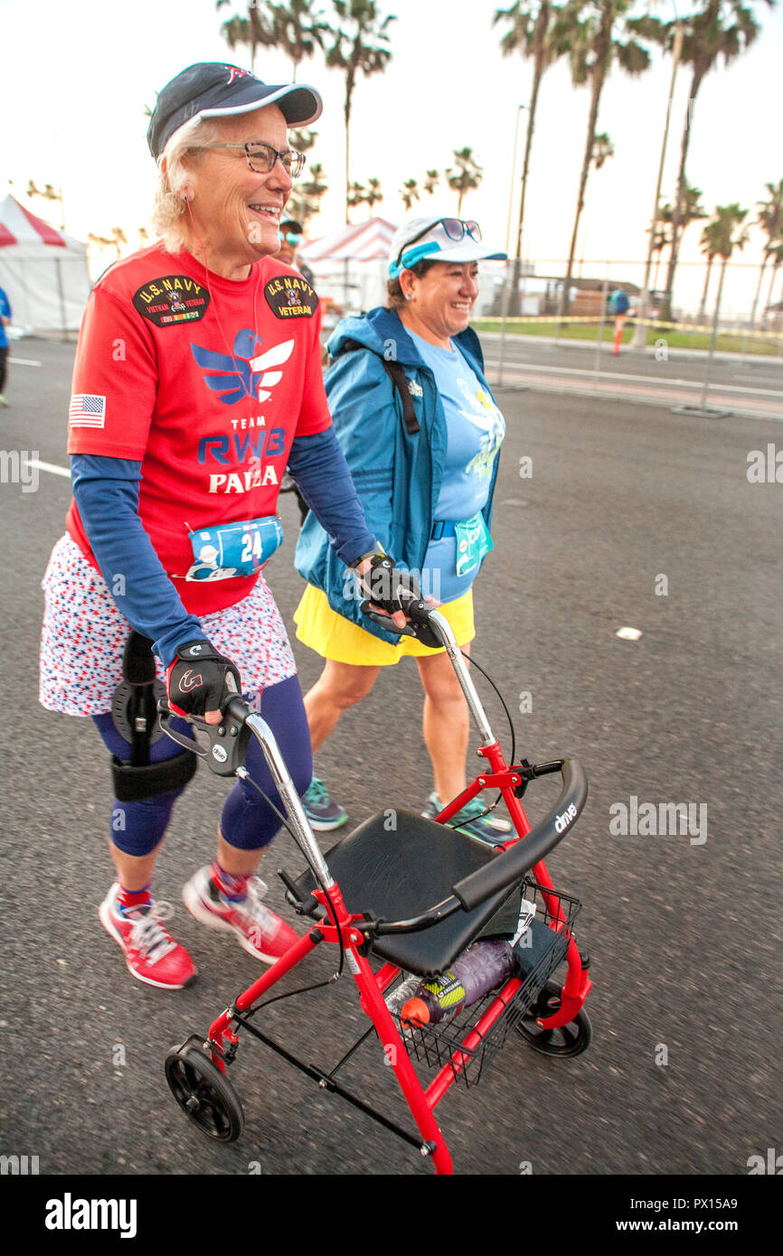 Accompanied by a partner, a enthusiastic handicapped US Navy senior woman veteran uses a walker to participate to a 5K foot race in Huntington Beach, CA. Stock Photo