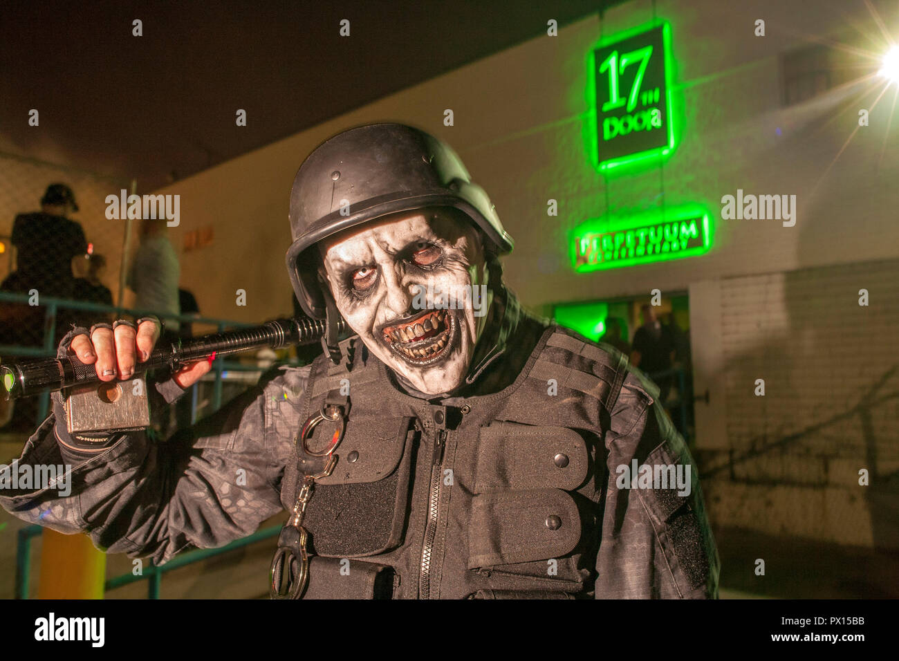 Waving a cattle prod and sporting a grotesque mask, the Main Guard inducts visitors to the 17th Door Haunted Experience on Halloween in Fullerton, CA. Stock Photo