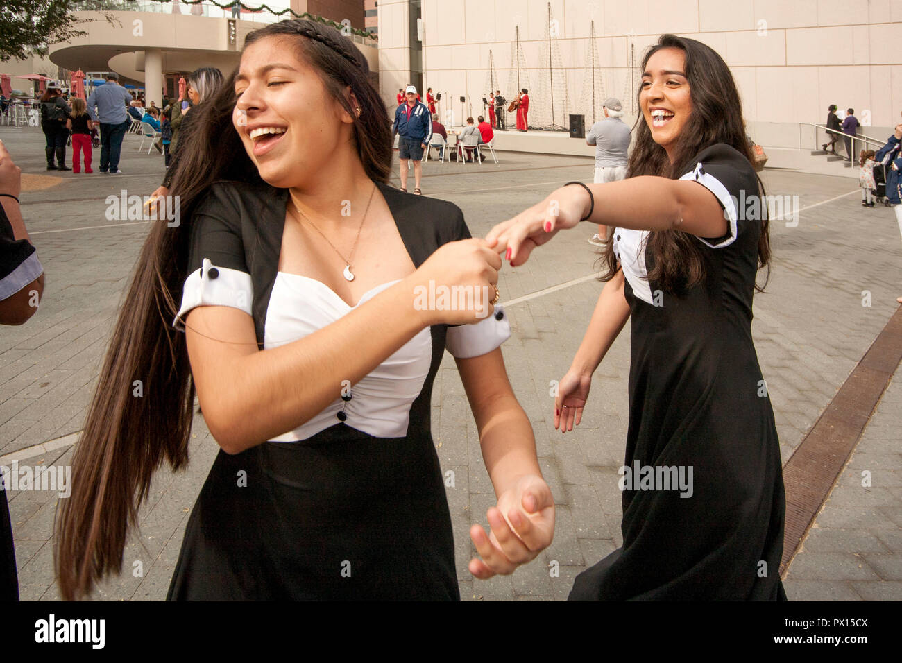 Hispanic teen girls dance to the music of a Mariachi band at an Outdoor ethnic festival in Costa Mesa, CA. Stock Photo