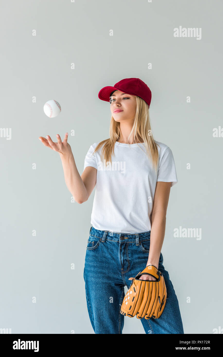attractive baseball player in red cap throwing up baseball ball