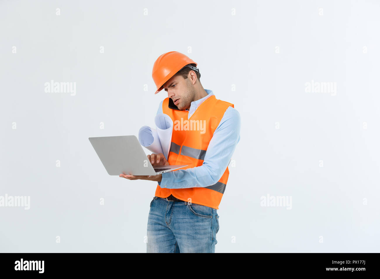 Engineer, architect, on busy face speaks on smartphone while holds blueprints. Man, foreman in helmet speaking on phone, red background. Architect calling engineer to fix plan. Communication concept Stock Photo