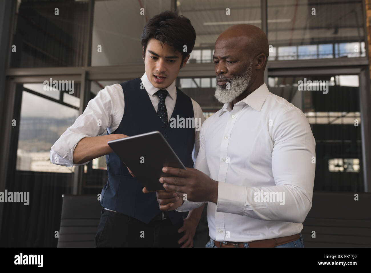 Executives discussing over digital tablet Stock Photo