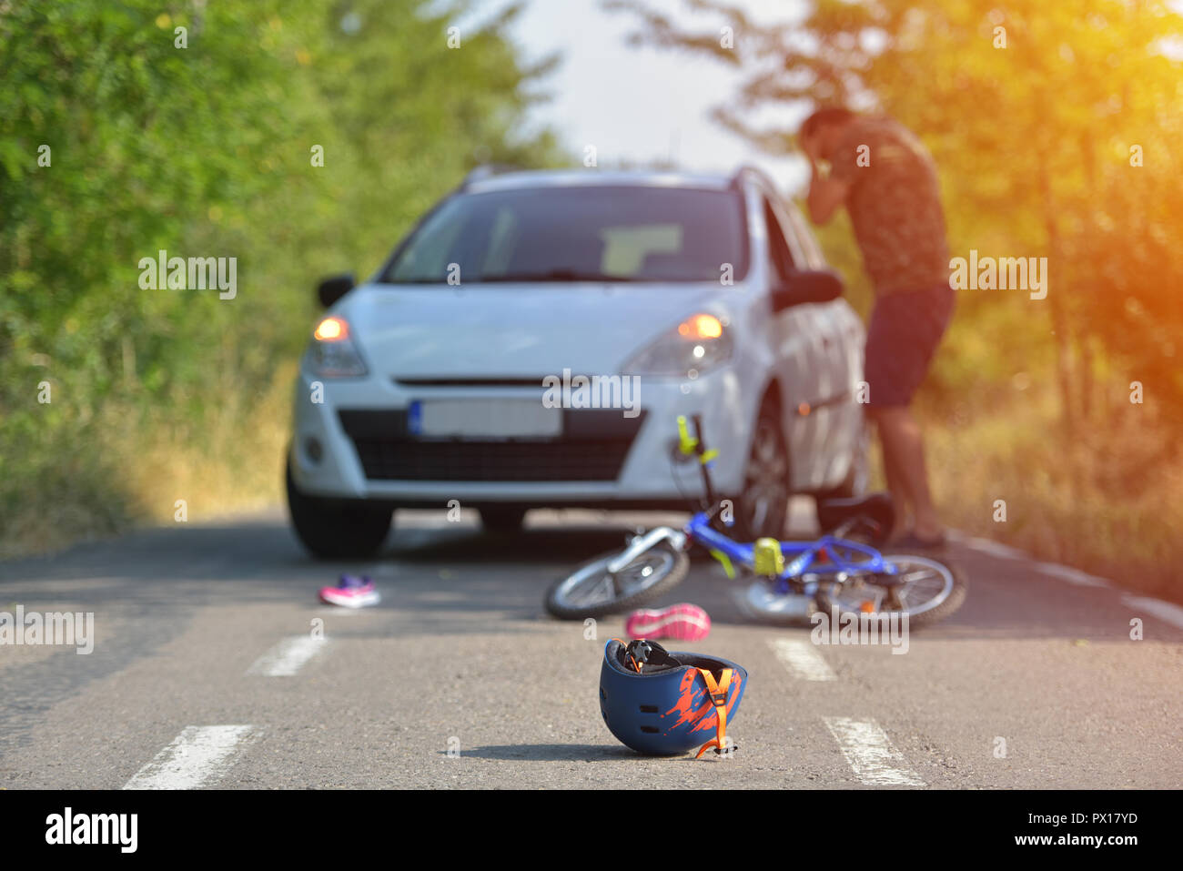 Close-up of a bicycling helmet fallen on the asphalt next to a bicycle after car accident on the street in the city Stock Photo