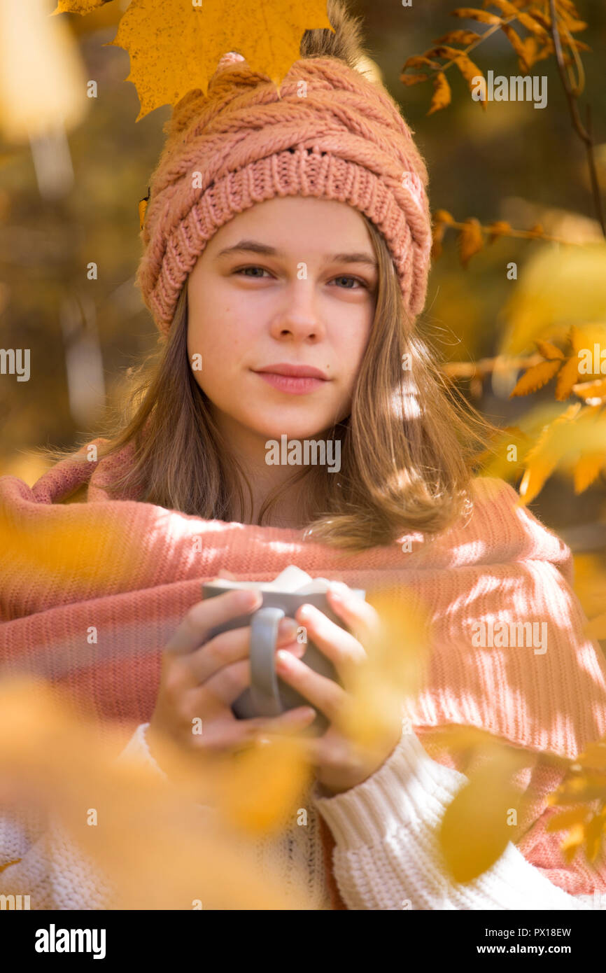 Portrait of pretty nice teenage girl drinking hot cocoa with marshmallows in autumn park Stock Photo