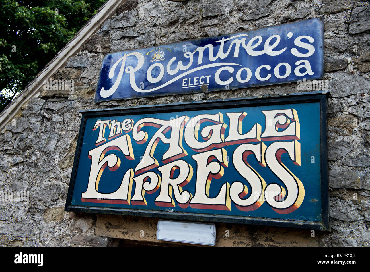 Antique Rowntrees cocoa and Eagle Printing Press metal sign on a building wall at Crich Tramway Museum in the village of Crich, Derbyshire, UK Stock Photo