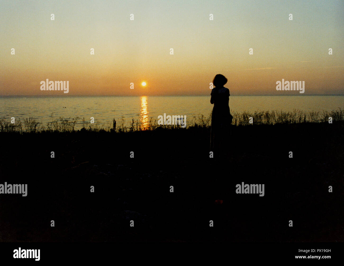 SUNSET in the sea with a women in silhouette Stock Photo - Alamy