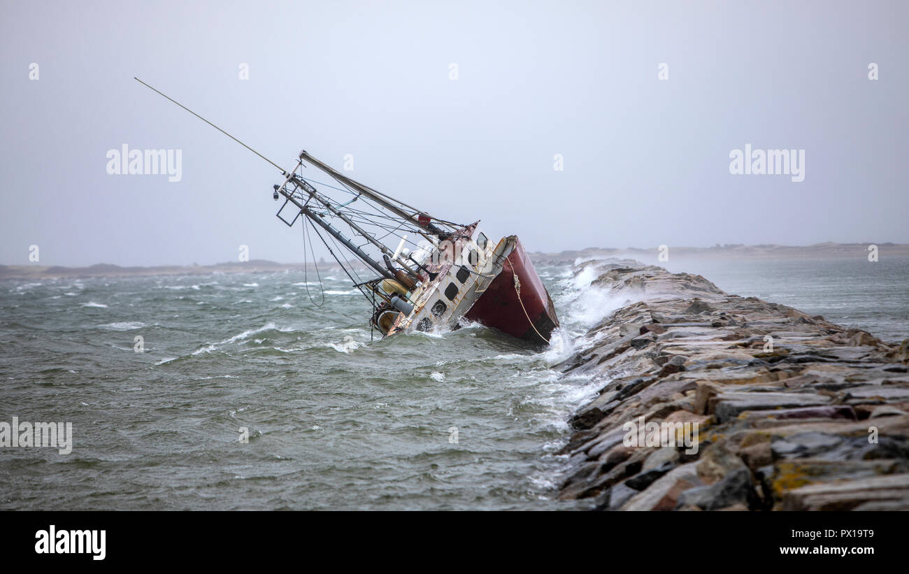 An abandoned derelict fishing boat stranded on a rock jetty. Stock Photo