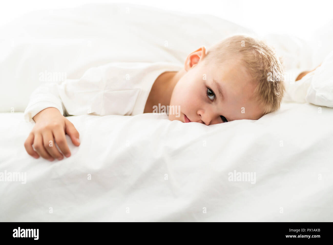 cute four years boy in white bedding Stock Photo Alamy