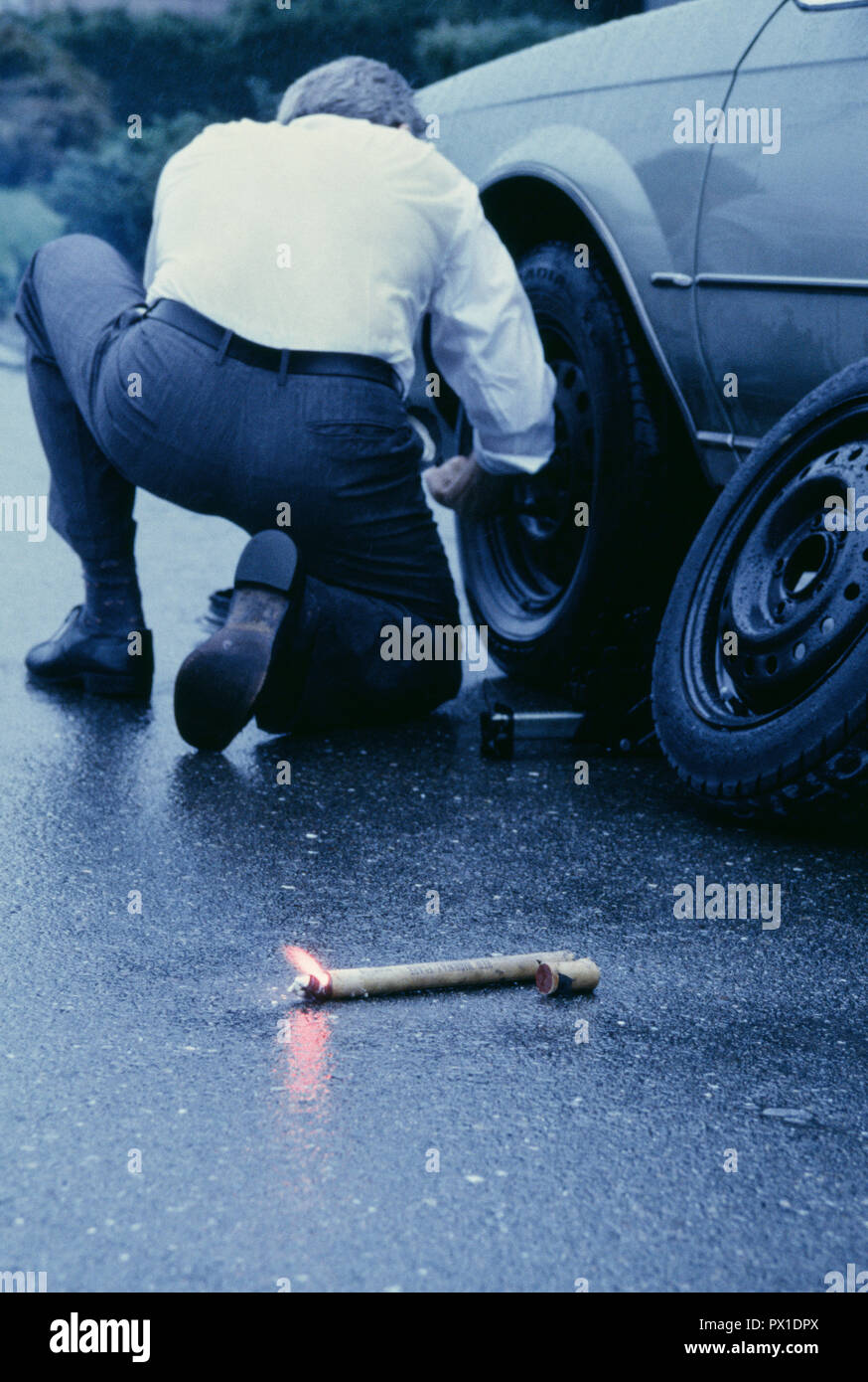 Businessman Changing a Flat Tire in the rain, USA Stock Photo