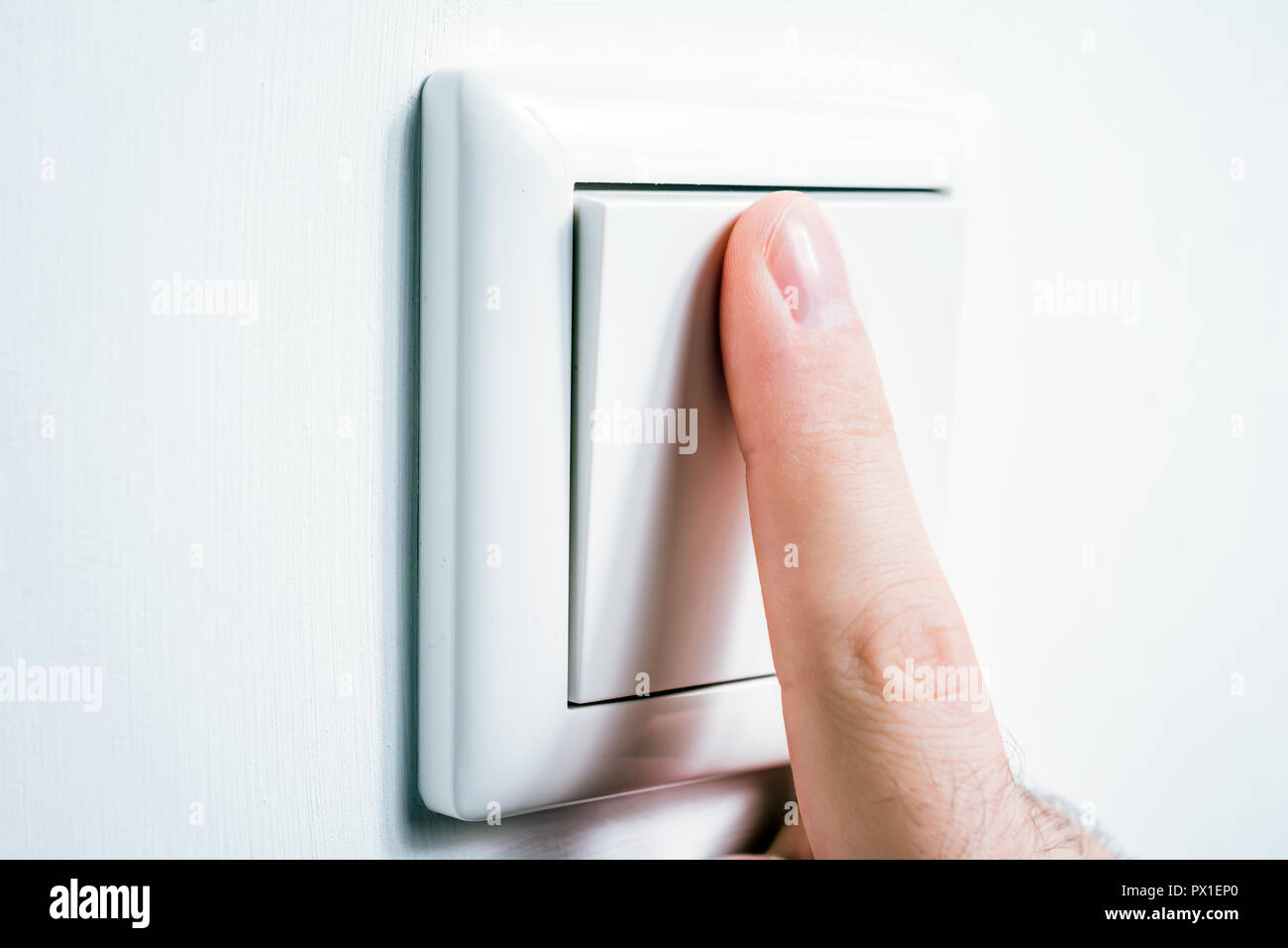 Male Finger Touching A Light Switch To Turn The Light On Or Off Stock Photo