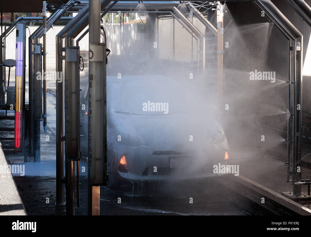 Car being spray washed in an automated car wash, bright purple, red and yellow indicator lights
