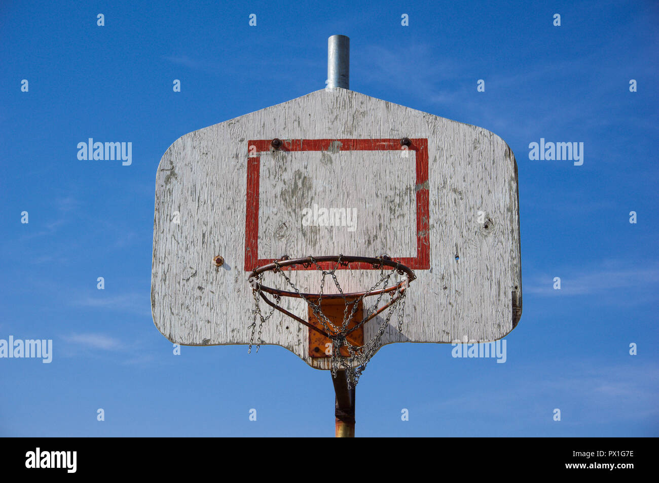 Close up of an outdoors old wooden backboard of a metal basketball hoop  with broken metal chain basket. Blue sky in the background Stock Photo -  Alamy