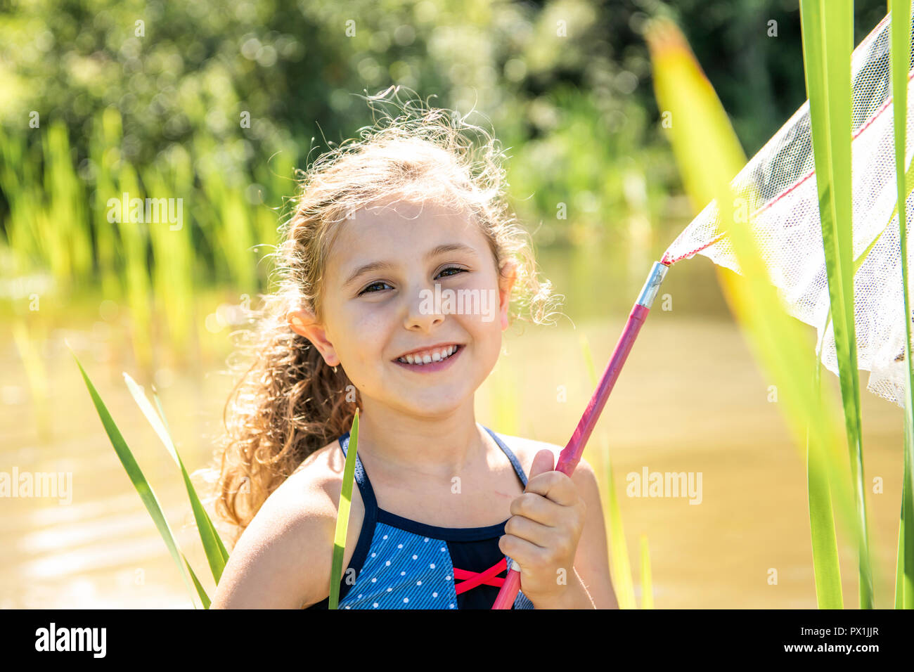 Cute girl fishing with a net on a lake Stock Photo Alamy