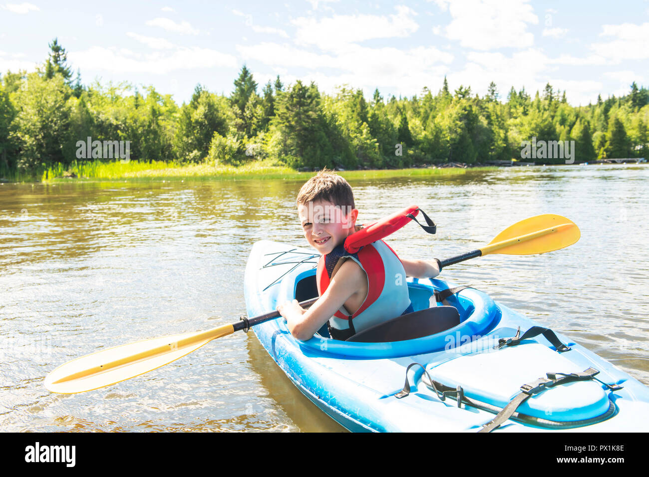 Summer vacation Portrait of happy cute boy kayaking the on river Stock Photo