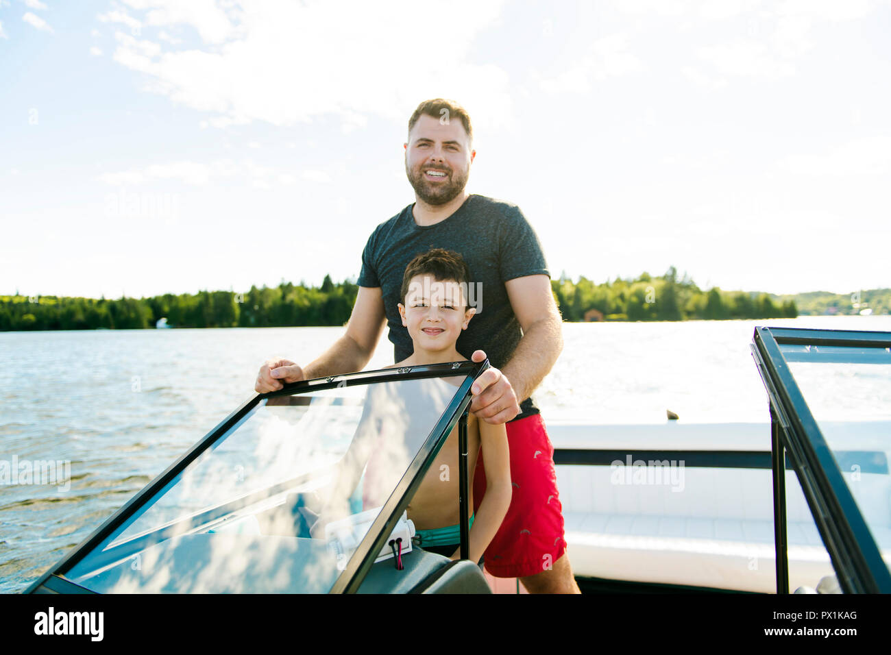 Man driving boat on holiday with his son kid Stock Photo