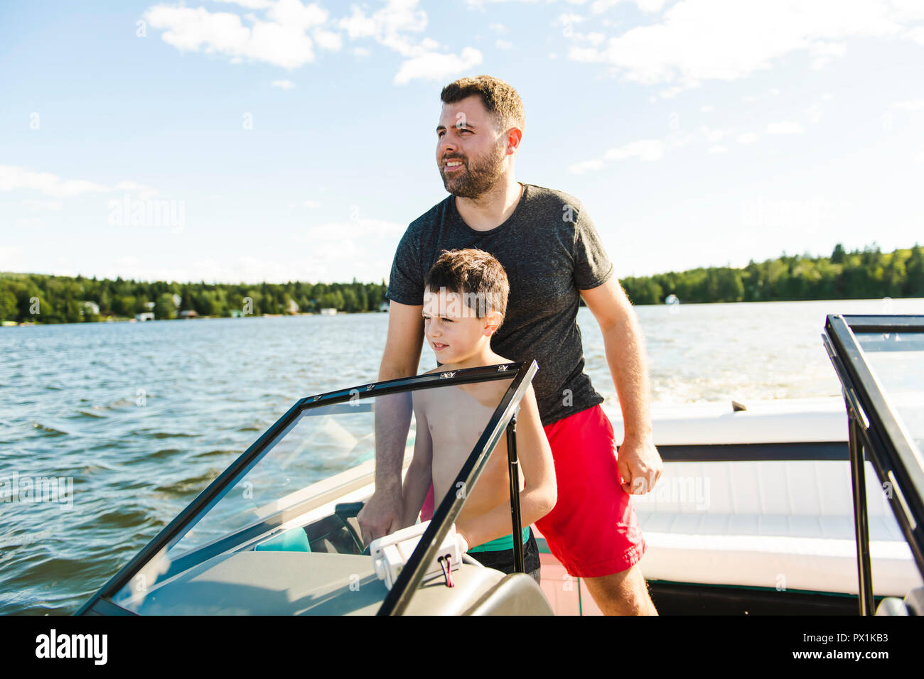 Man driving boat on holiday with his son kid Stock Photo