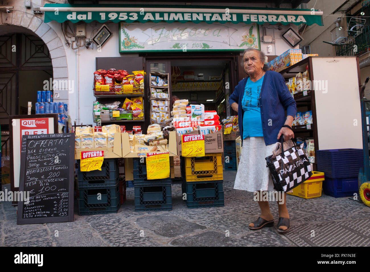 A shopper stands outside a mini-market in Naples Stock Photo