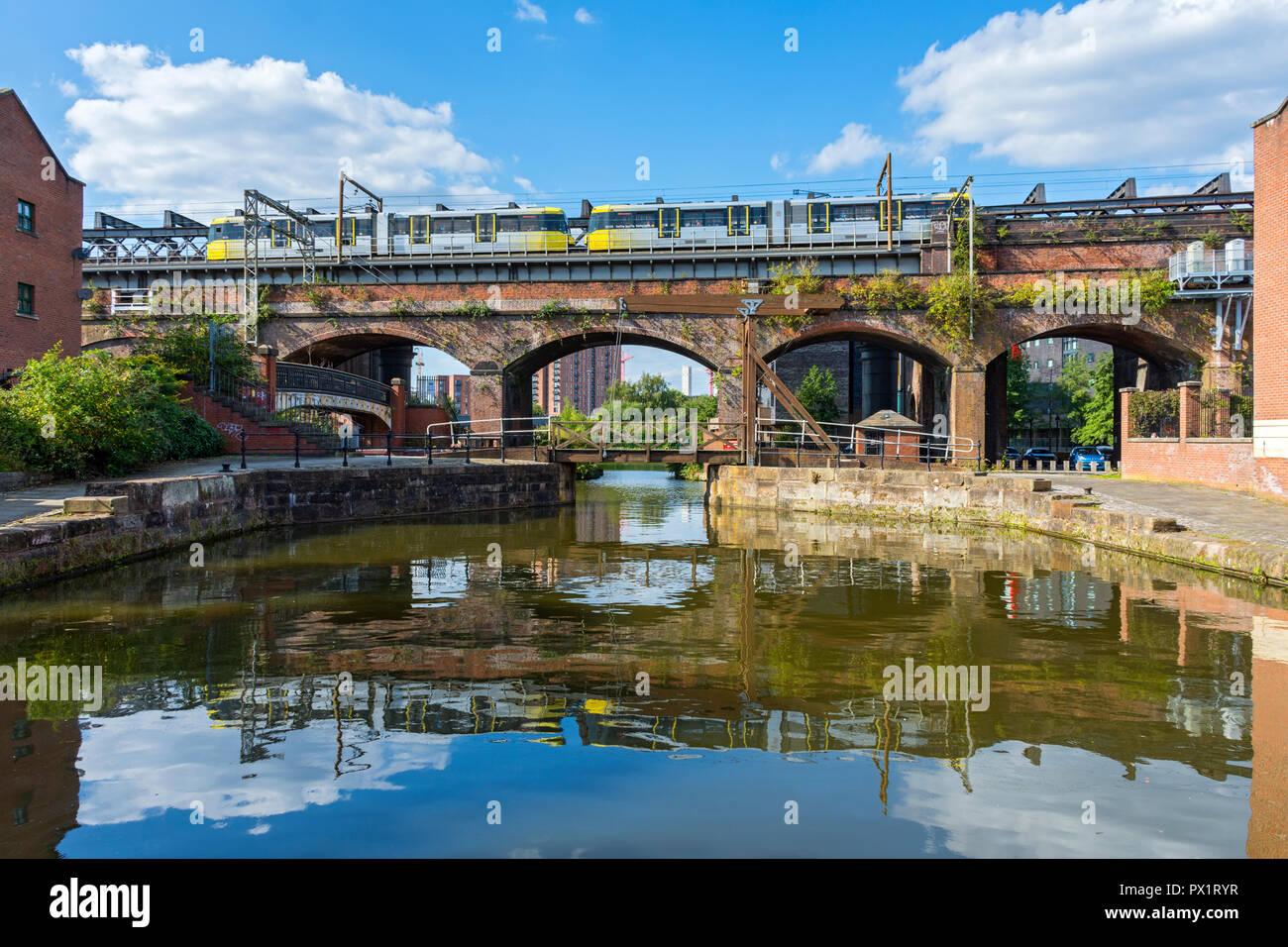 Metrolink tram on a Victorian railway viaduct, and a modern footbridge at Slate Wharf on the Bridgewater Canal at Castlefield, Manchester, England, UK Stock Photo