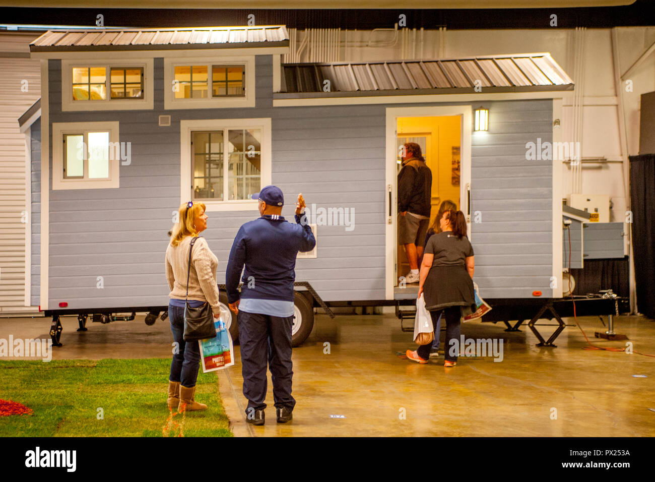 Curious visitors inspect a mobile 8 x 20-foot Tiny House exhibited at a home show in Costa Mesa, CA, boasts a queen-size bed and a loft. Stock Photo