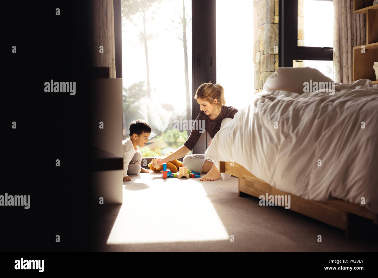 Mother and little son are playing with different developing toys in bedroom. Young woman spend fun time with her son. Mum and kid playing with wooden Stock Photo
