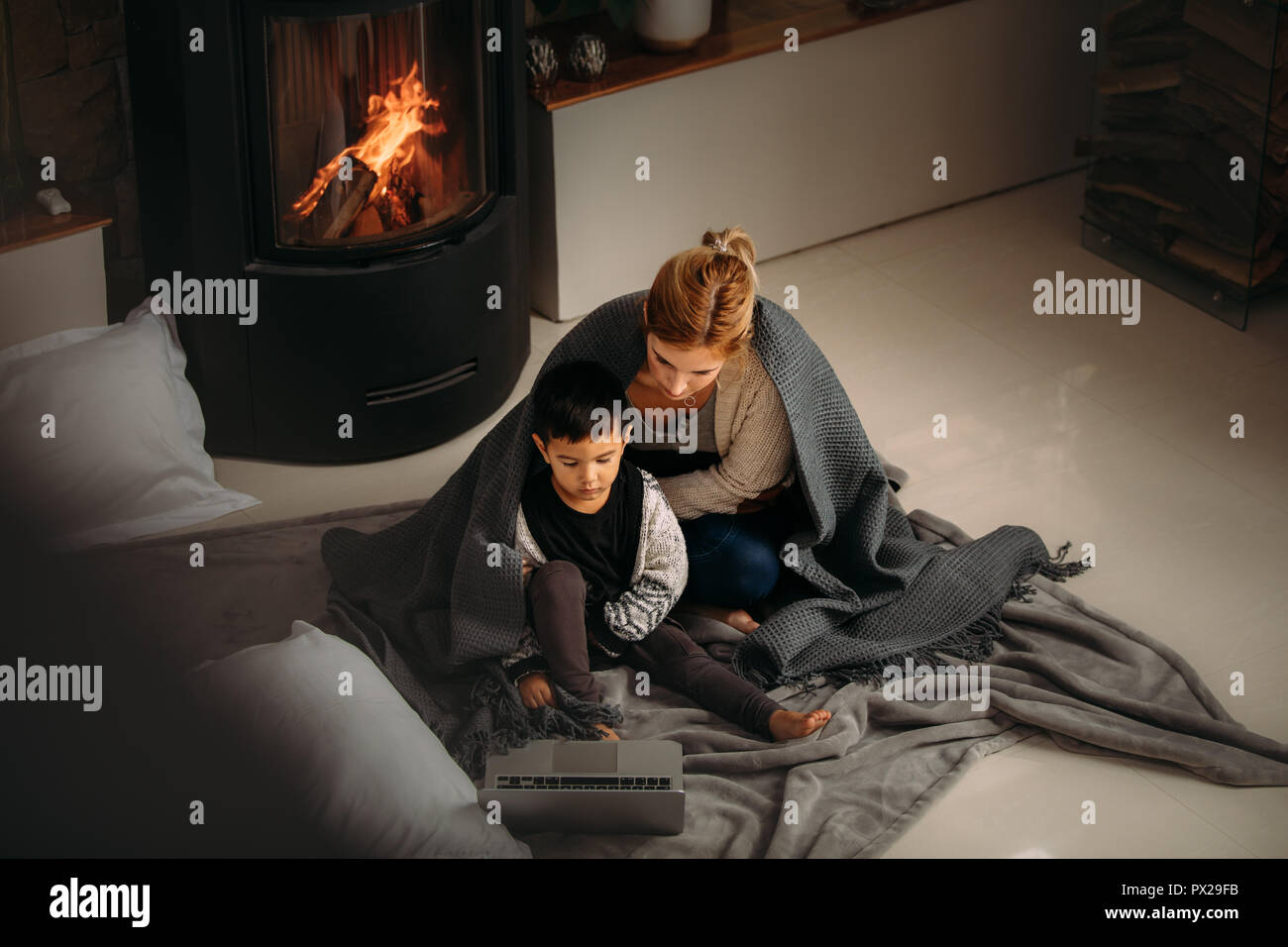 Woman And A Little Boy With Blanket Sitting On Floor Looking At