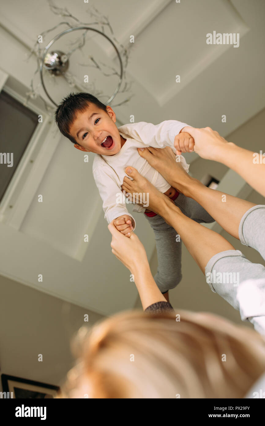 Woman holding a little boy on her legs and playing. Mother and son enjoying a morning in a bedroom. Stock Photo