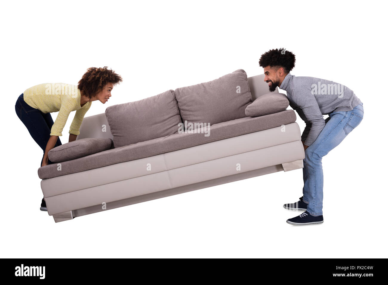 Side View Of An African Couple Carrying Sofa On White Background Stock Photo