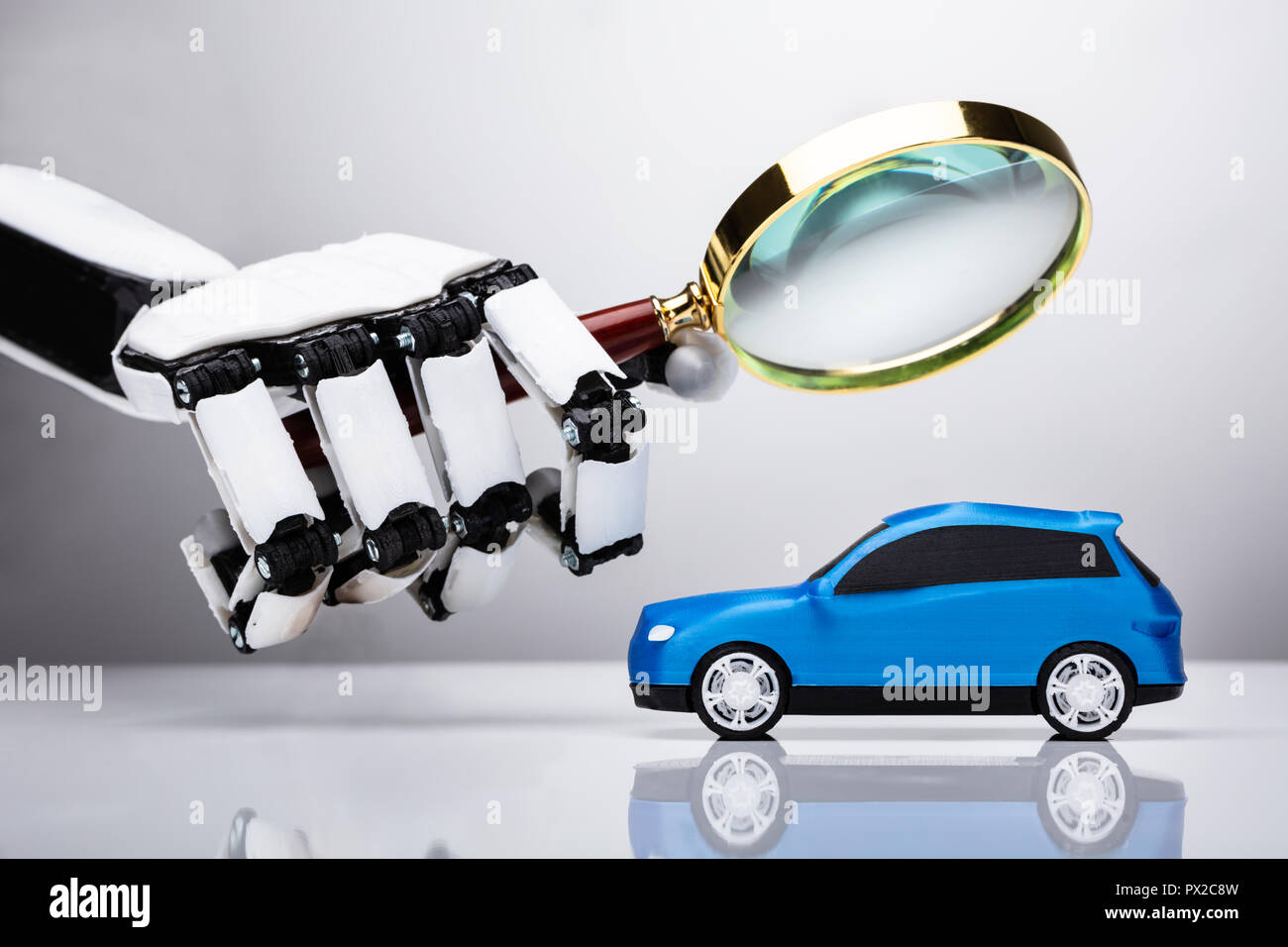 Robot Examining Blue Car With Magnifying Glass Stock Photo