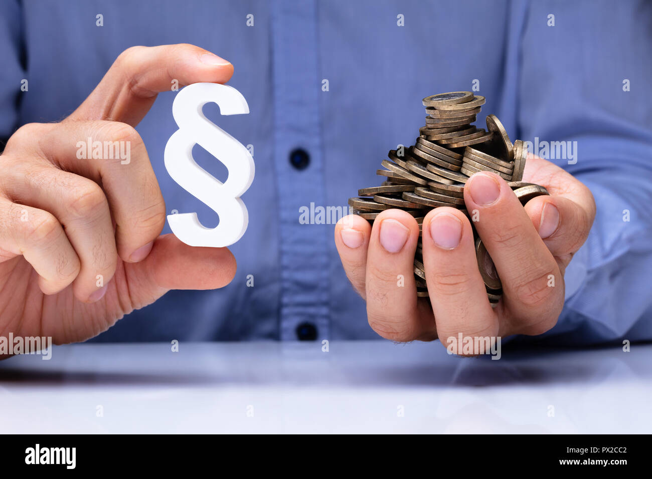 Close-up Of A Person's Hand Holding White Paragraph Symbol And Coins Stock Photo