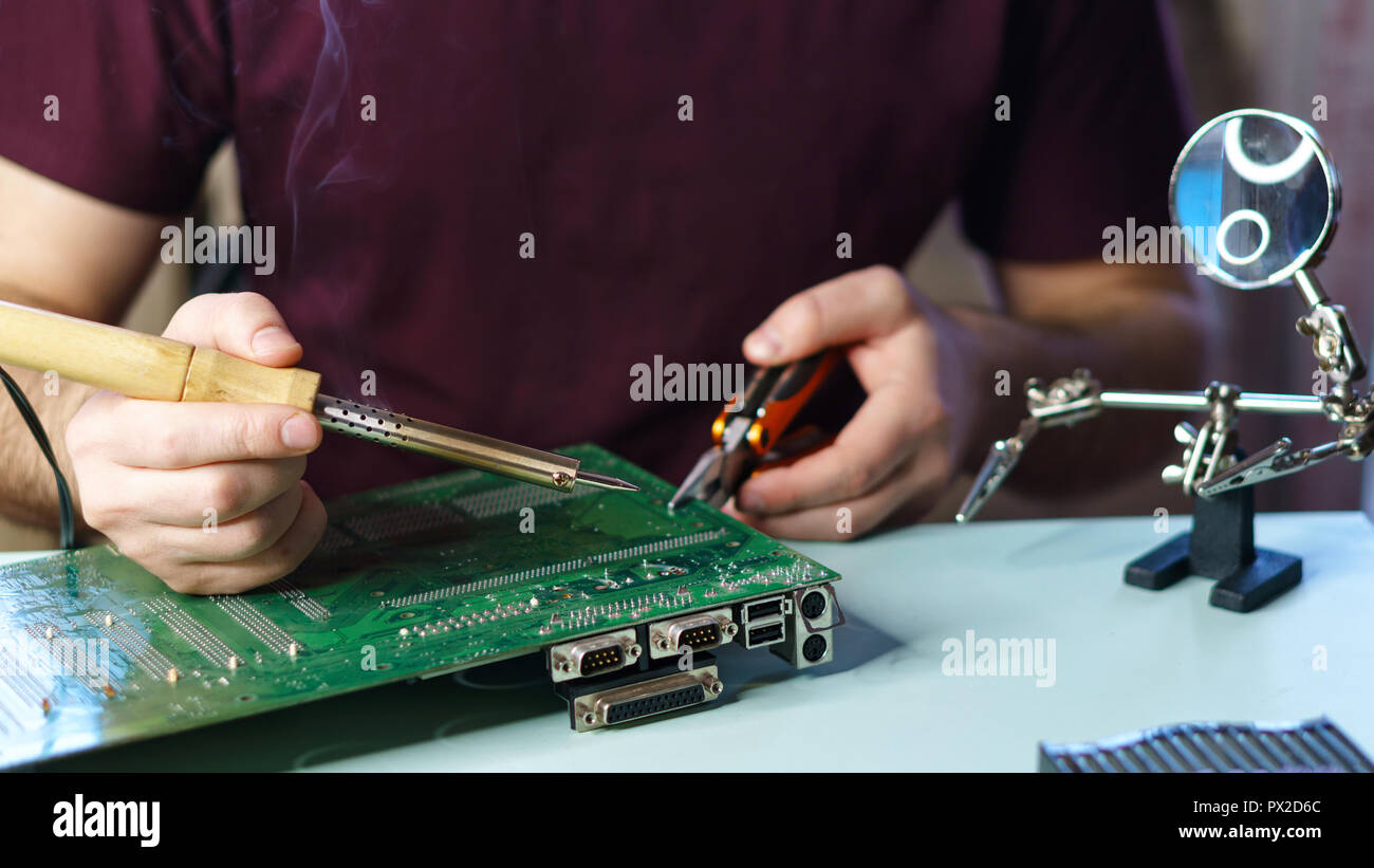 Repair motherboard. Man soldering solder the contacts from the