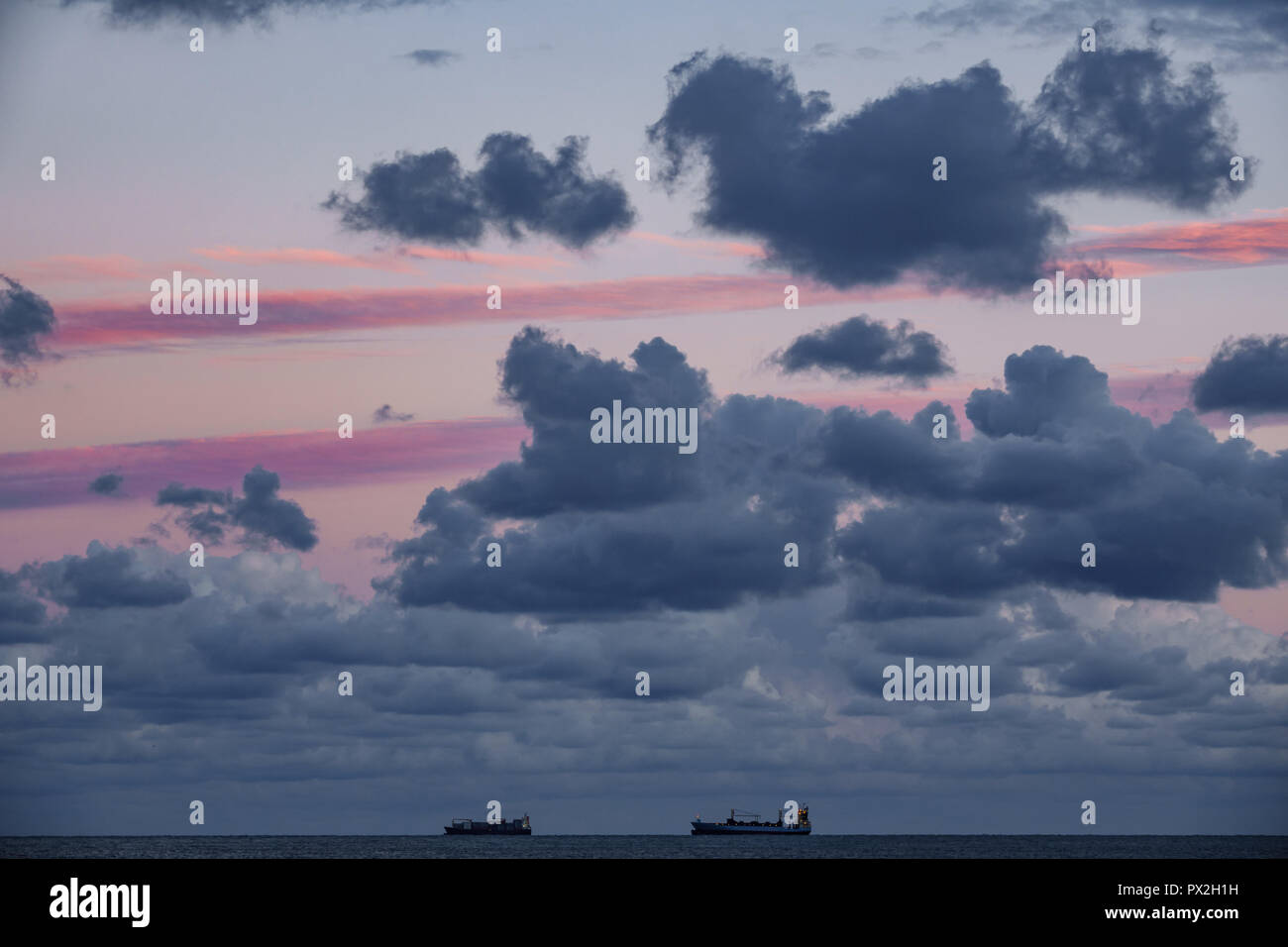 Two cargo ships on top of the horizon at sunset Stock Photo - Alamy