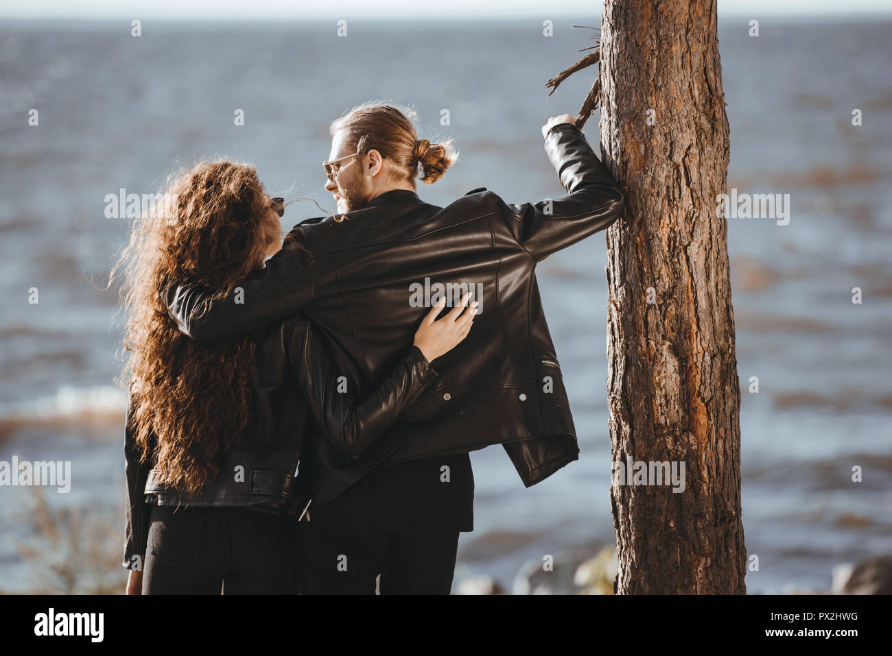 back view of couple in black leather jackets hugging and looking at ...