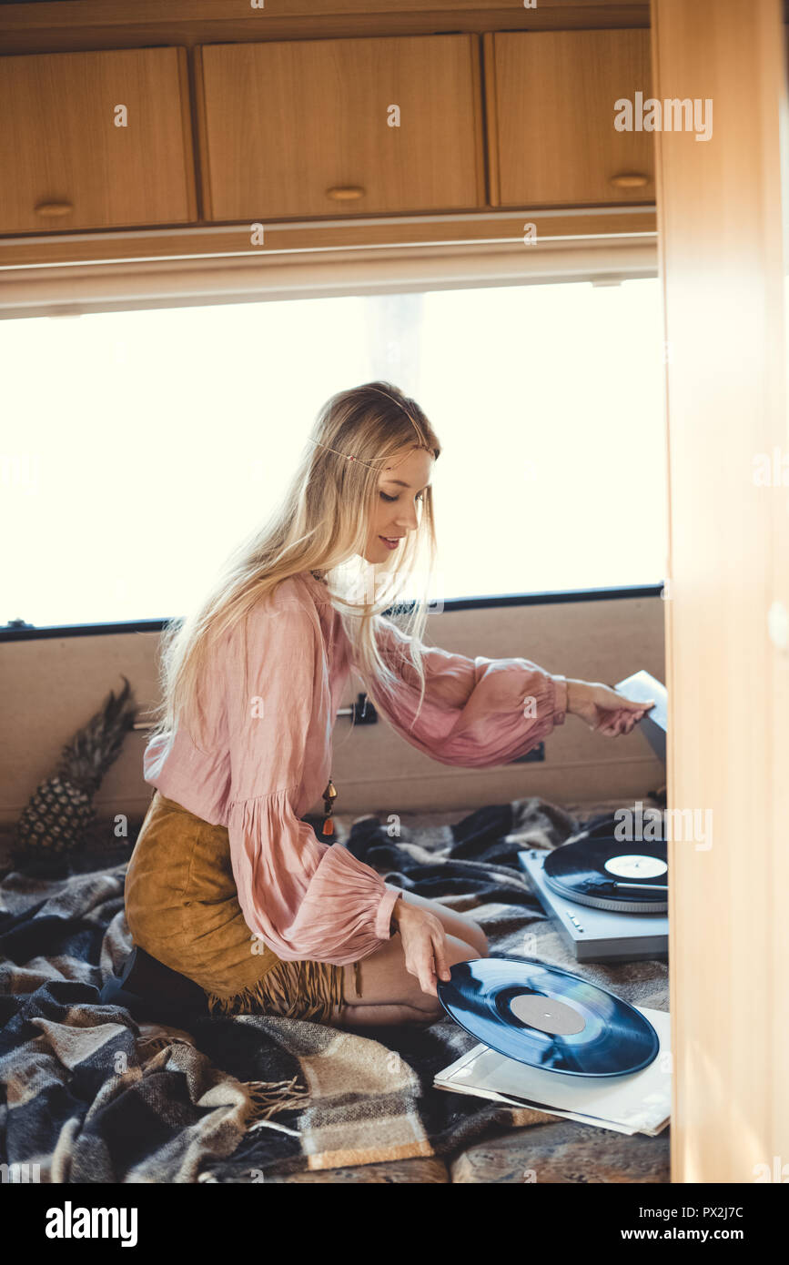 beautiful hippie girl putting vinyl record into player inside camper van Stock Photo