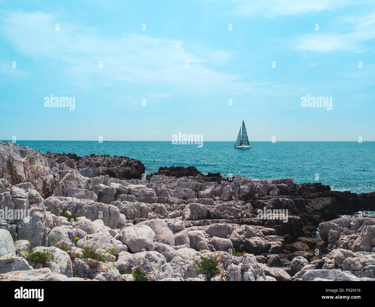 White rocks and mediterranean sea with sailing boat and blue sky Stock Photo