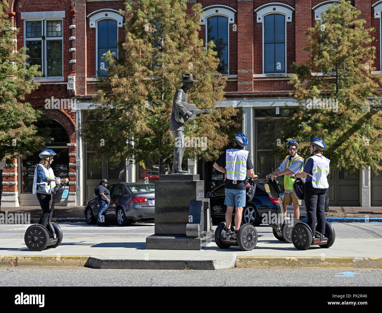 Tourists on a Segway in a tour group stop to view the Hank Williams memorial bronze statue in Montgomery Alabama, USA. Stock Photo