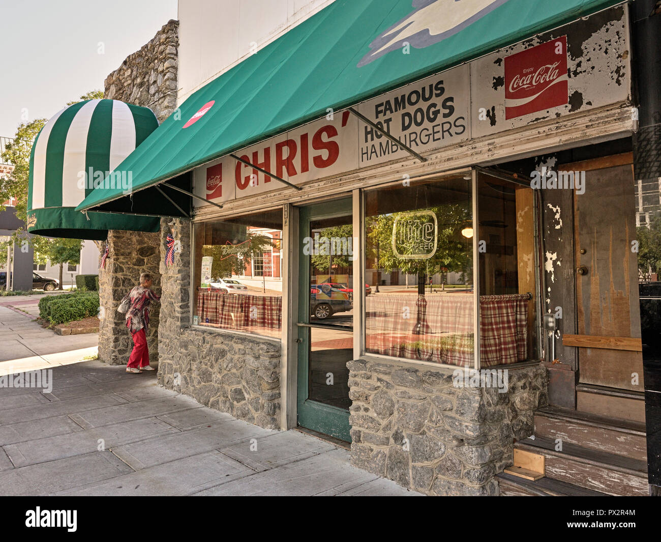 Front exterior entrance of Chris' Hot Dogs restaurant with a senior or elderly woman or lady entering in Montgomery Alabama, USA. Stock Photo