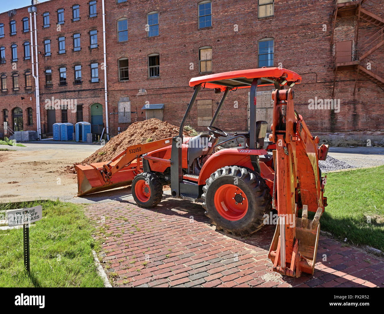 Orange Kubota HST tractor front loader with backhoe attachment on a construction site in Montgomery, Alabama, USA. Stock Photo