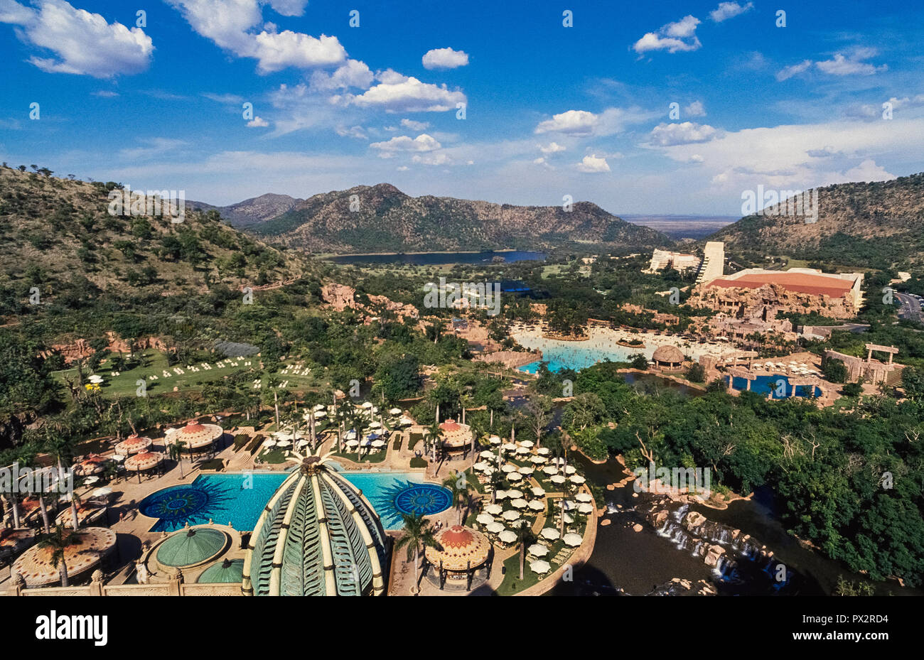 In the North West Province of South Africa is the world-renowned Sun City holiday resort, a vast playground that offers vacationers everything from a water park with a wave pool, golf courses, a gambling casino, hot-air balloon rides, and even animal safaris in the adjacent game park. Guests have a choice of four lodgings, including The Palace of the Lost City, a luxurious 5-star hotel from the top of which this panoramic view was photographed. Stock Photo