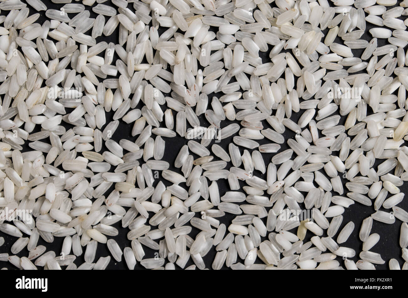 White rice scattered on an isolated black background, rice mountains ...