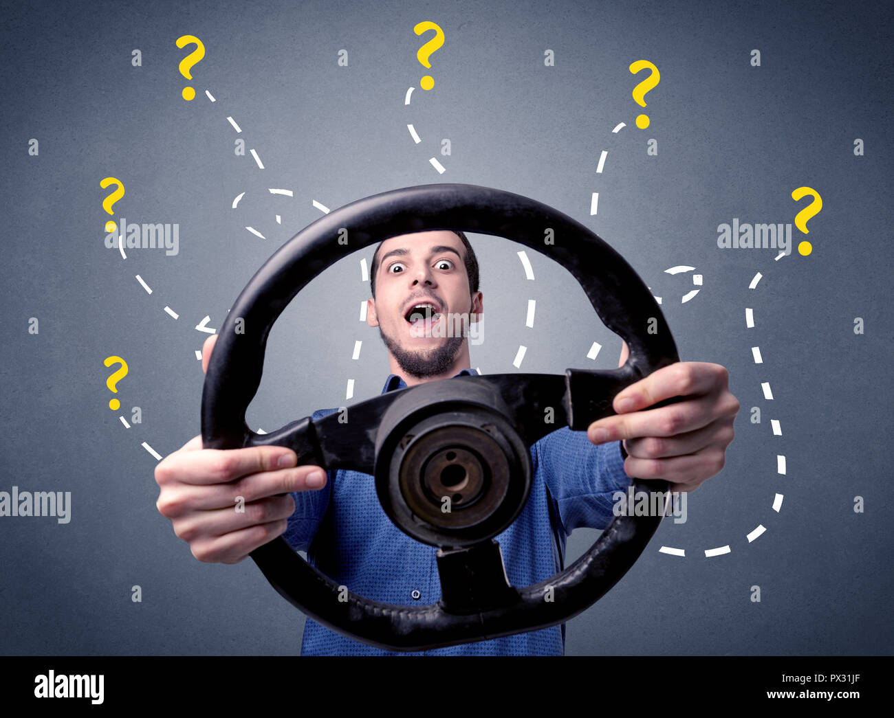 Young man holding black steering wheel with question marks around him
